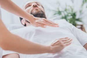 Manos de un terapeuta Reiki sobre su paciente. El Reiki alivia estrés, reduce ansiedad, dolor crónico, mejora el sueño y promueve bienestar emocional y espiritual, equilibrando las energías del cuerpo.